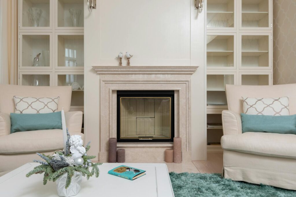 Interior of modern living room with armchairs on carpet near table next to marble pink fireplace